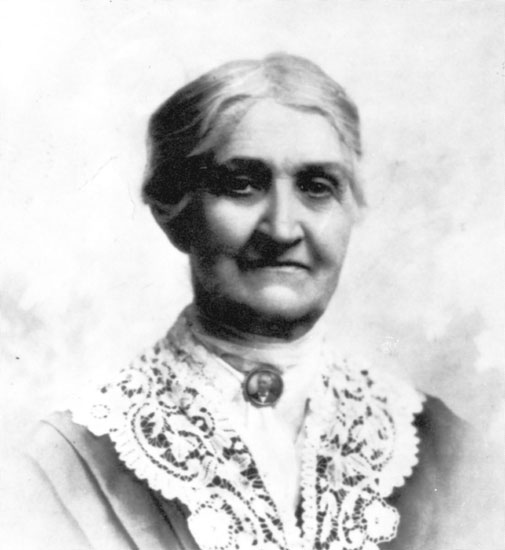 Older white woman wearing a dress with a portrait brooch and lace collar