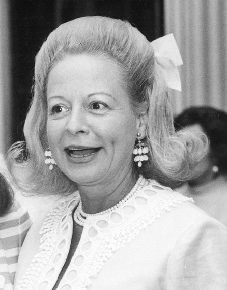 Older white woman smiling in pearl earrings and necklace