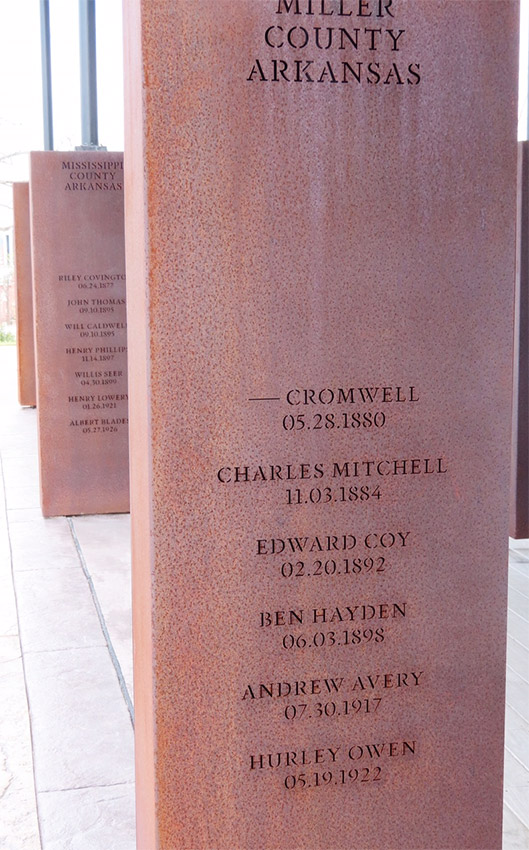 Rust-colored metal rectangle engraved with names and locations