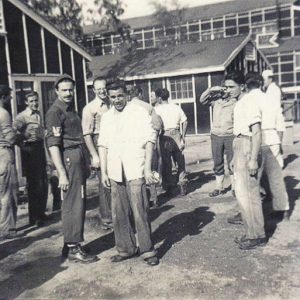 Young white men standing outside barracks buildings
