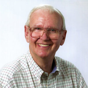 Old white man with glasses smiling in checkered shirt