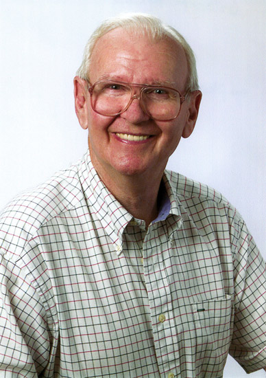 Old white man with glasses smiling in checkered shirt
