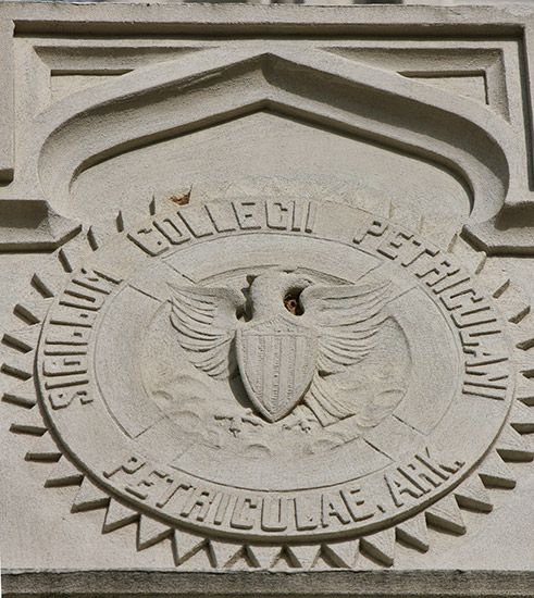 Round logo with eagle Latin text and shield etched onto building