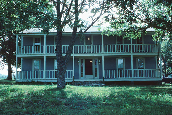 Blue and white two-story house with covered porch and covered balcony across the entire front