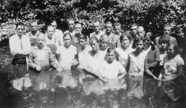 Group of white men and women standing in body of water
