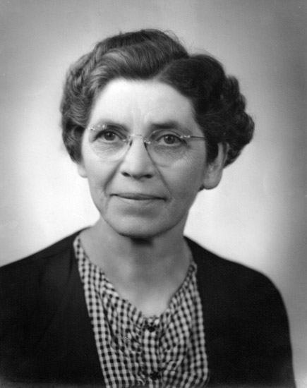 Older white woman with glasses in checkered shirt and sweater