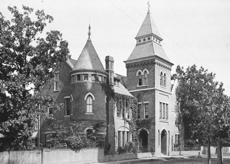 Three-story building with towers, arched entrances, and arched windows