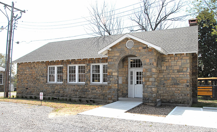 Stone brick building with covered entrance on gravel parking lot