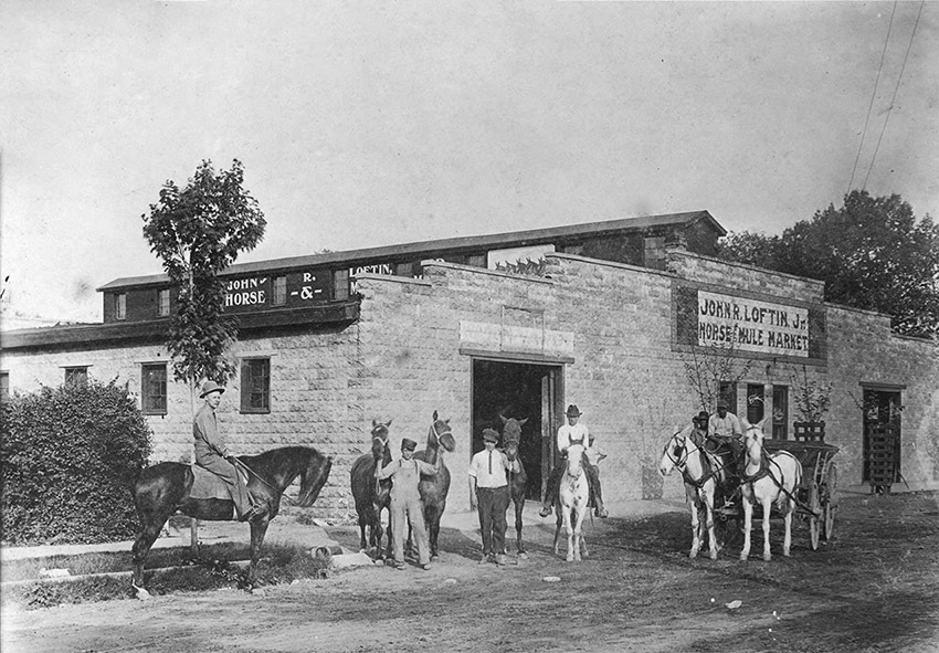 White and African-American men with horses and carriage outside of brick building