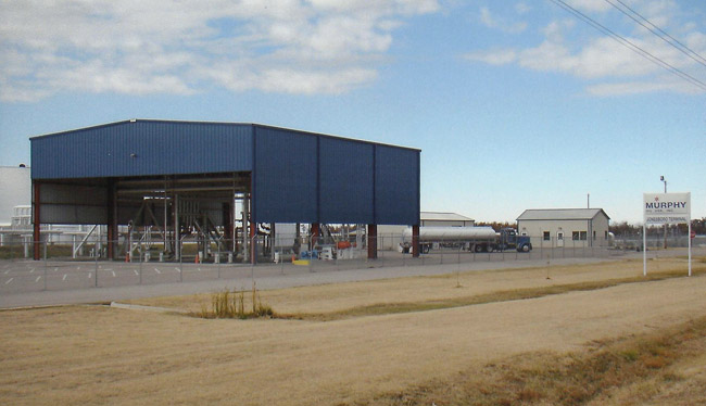 large blue metal building with machinery and tanker truck