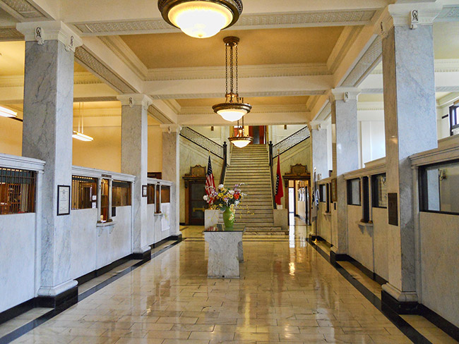 Hallway with columns hanging lighting fixtures and staircase in the background