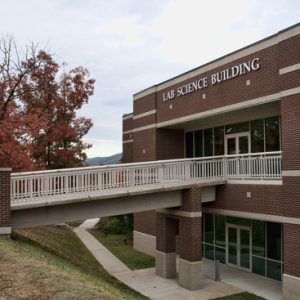 Two-story brick building with walking bridge and "Lab Science Building" written above the entrance