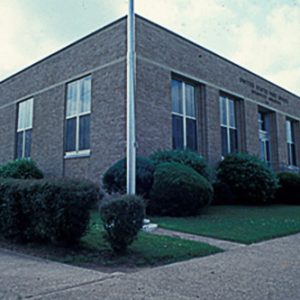 Single-story brick building with flag pole and sidewalk