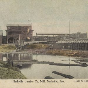 Multistory mill buildings with smoke stacks and logs floating on water in the foreground