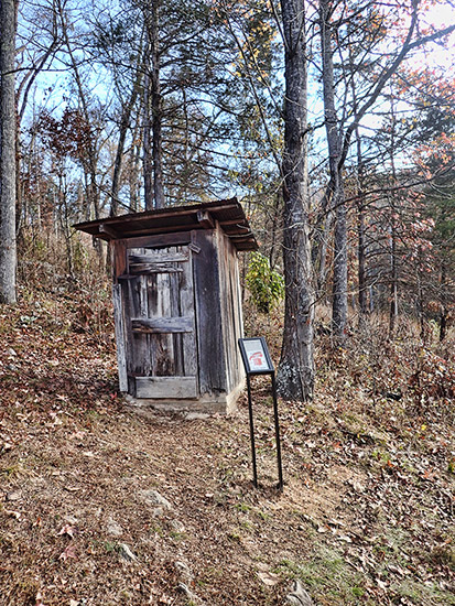 Outhouse and interpretation panel in forest