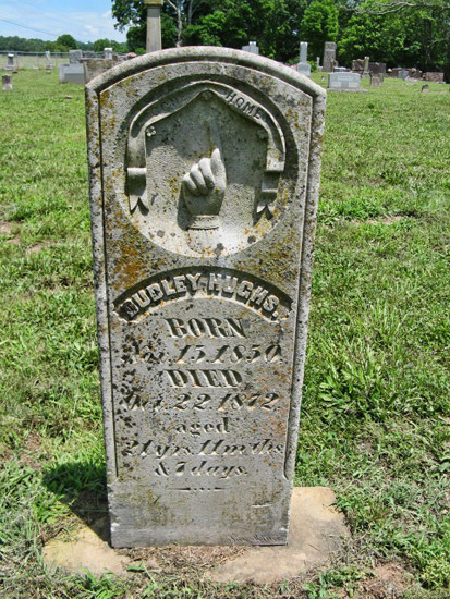 Hand with pointed finger on weathered gravestone in cemetery