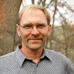 White man with glasses and mustache in collared shirt