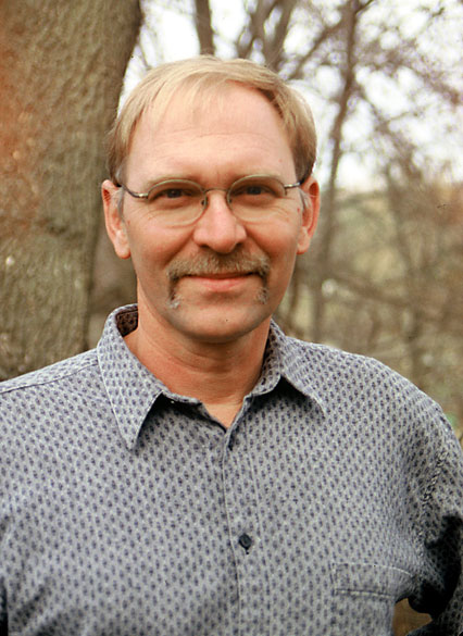 White man with glasses and mustache in collared shirt