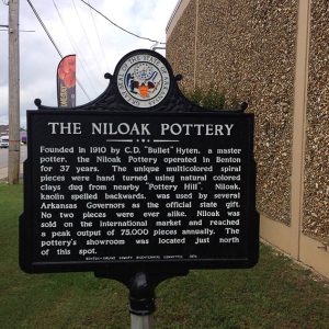 Historical marker sign on street with buildings behind it