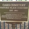 "Oaks Cemetery Historic Black Cemetery Established 1867" plaque on iron fence