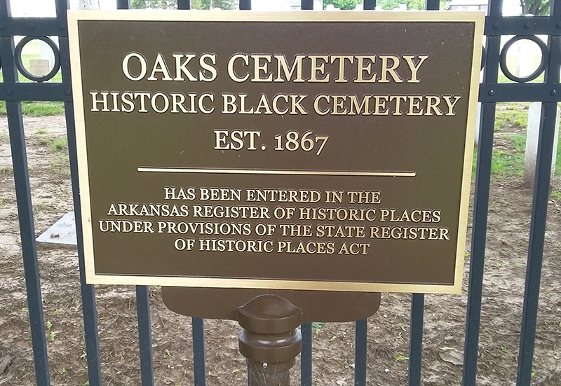 "Oaks Cemetery Historic Black Cemetery Established 1867" plaque on iron fence