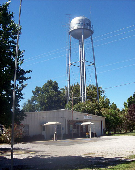 Metal building with water tower and parking lot