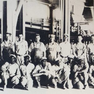 Group of white and African-American men posing for a group photo in factory