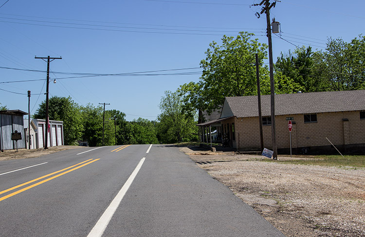 Single-story brick stores and garage building on two-lane road
