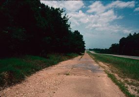 Section of old and crumbling highway with newer road parallel to it