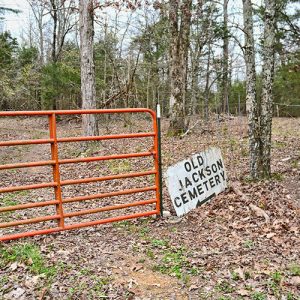 Orange metal gate and "Old Jackson Cemetery" sign on dirt road