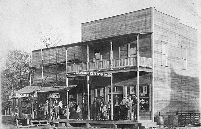 two-story storefront including a restaurant in front with group of adults and children on front porch