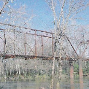 Steel truss bridge over river with trees on both shores