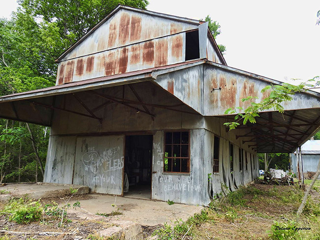 Abandoned rusting multistory gin building with covered entrance and walkway