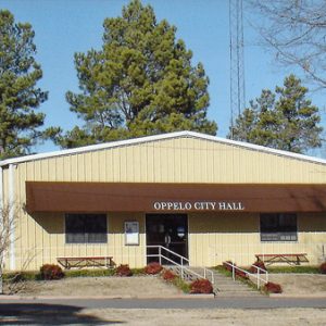 Metal building with four garage doors and "Oppelo City Hall" displayed on awning above the entrance