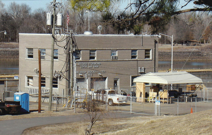 Two-story building next to river with parking lot and electrical poles