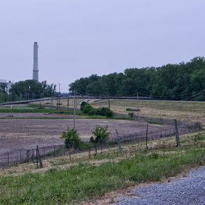 Industrial buildings with smokestack beyond barbed wire fence