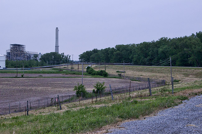 Industrial buildings with smokestack beyond barbed wire fence