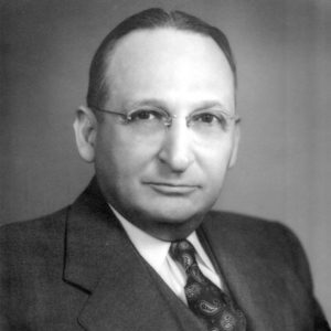 White man in glasses wearing a suit and vest