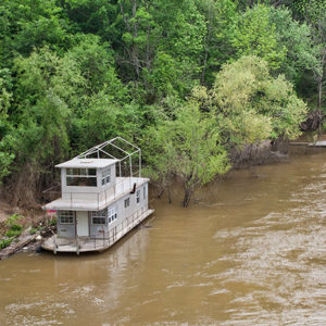 Houseboat on muddy river with trees in the background