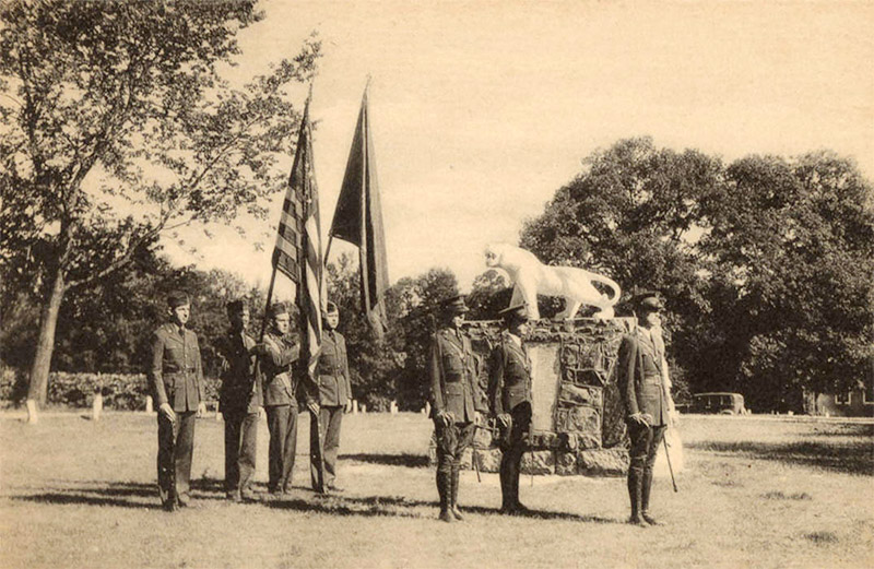 Young white men with flags in military uniform next to tiger statue