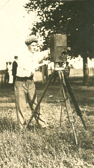 Young white man in hat with a camera on a tripod