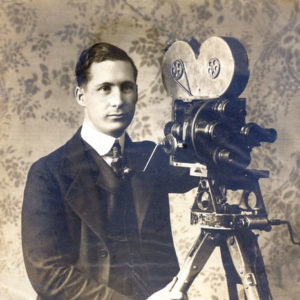 Young white man in suit and tie with camera on a tripod
