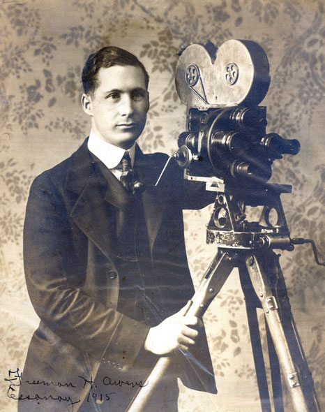 Young white man in suit and tie with camera on a tripod