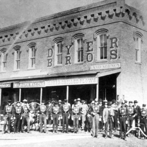 Group of men in uniforms in front of "Dyer Bros." land agency
