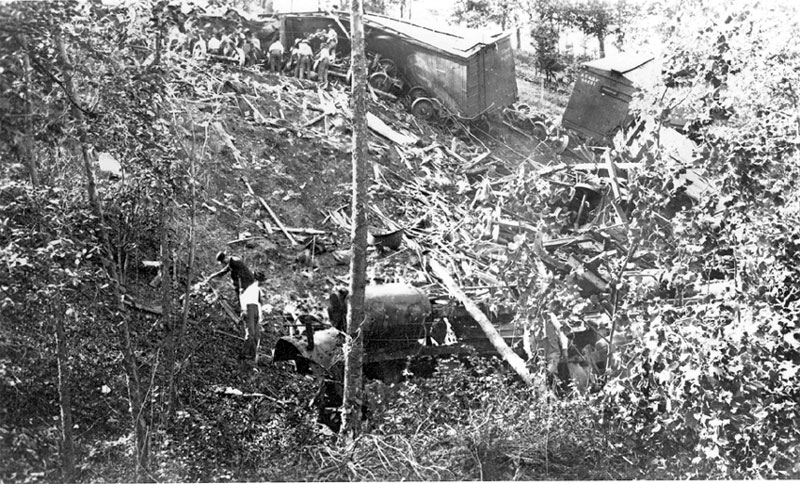 Men looking through the wreckage of a train crash on a wooded hill side