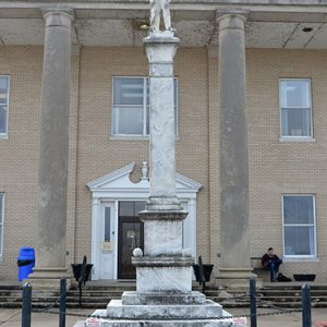 stone monument featuring soldier on pedestal in front of two-story brick building