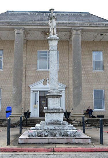 stone monument featuring soldier on pedestal in front of two-story brick building