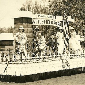 White women and older white man atop a parade float outside park entrance