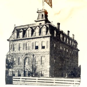 Four-story building with a tower and a flag pole