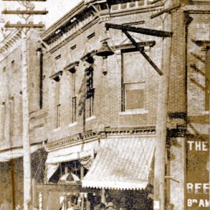 Crowd of men in hats in front of two-story building